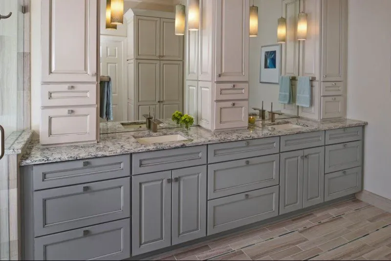 a bathroom with white cabinets and marble counter tops