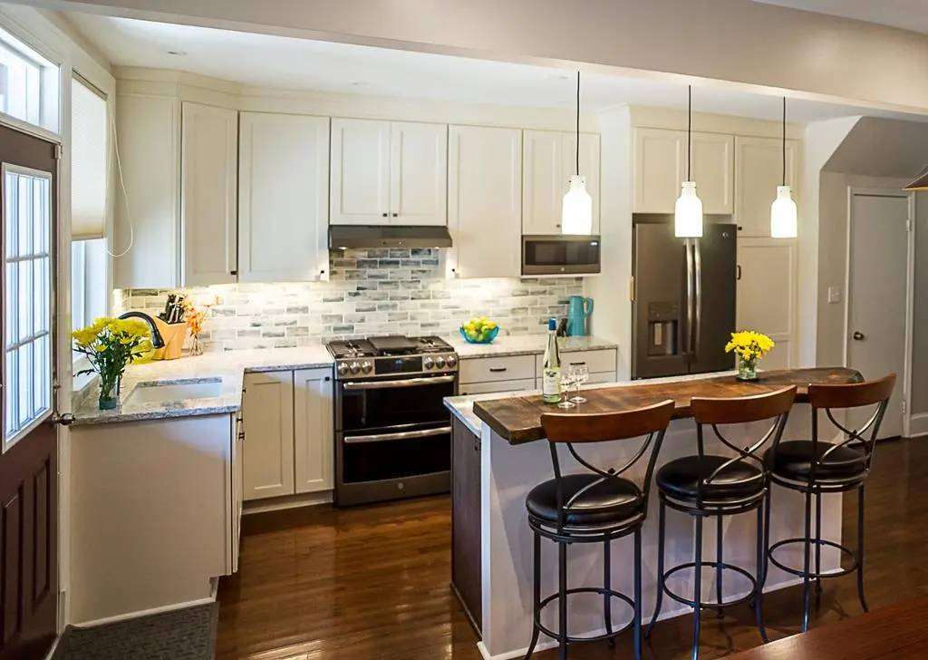 a kitchen with white cabinets and a bar stools