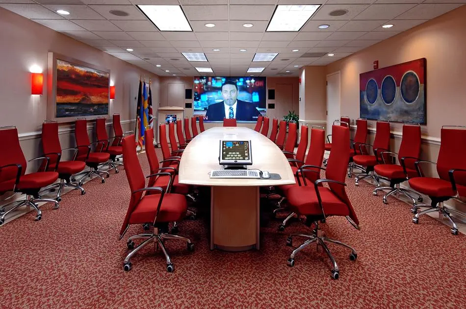 a conference room with a laptop and red chairs