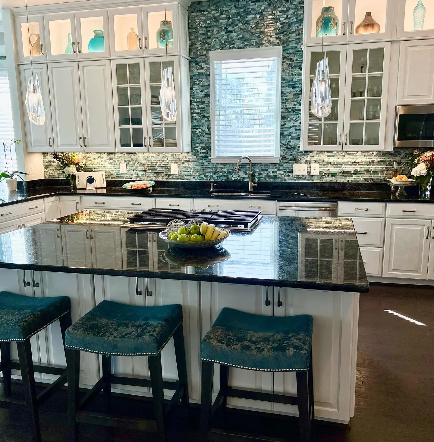 a kitchen with a black countertop and blue stools
