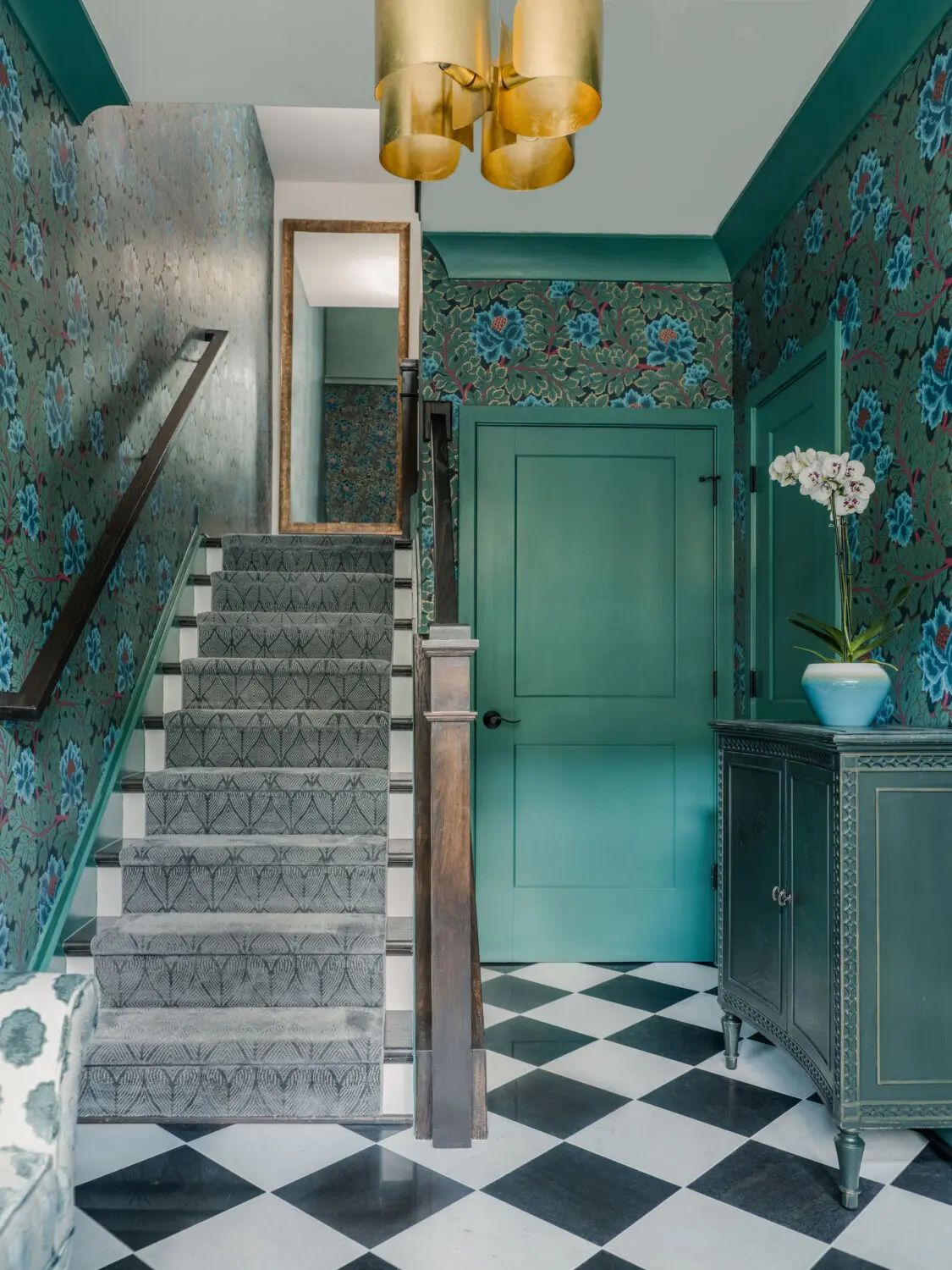 a staircase with a flower wallpaper and a green door