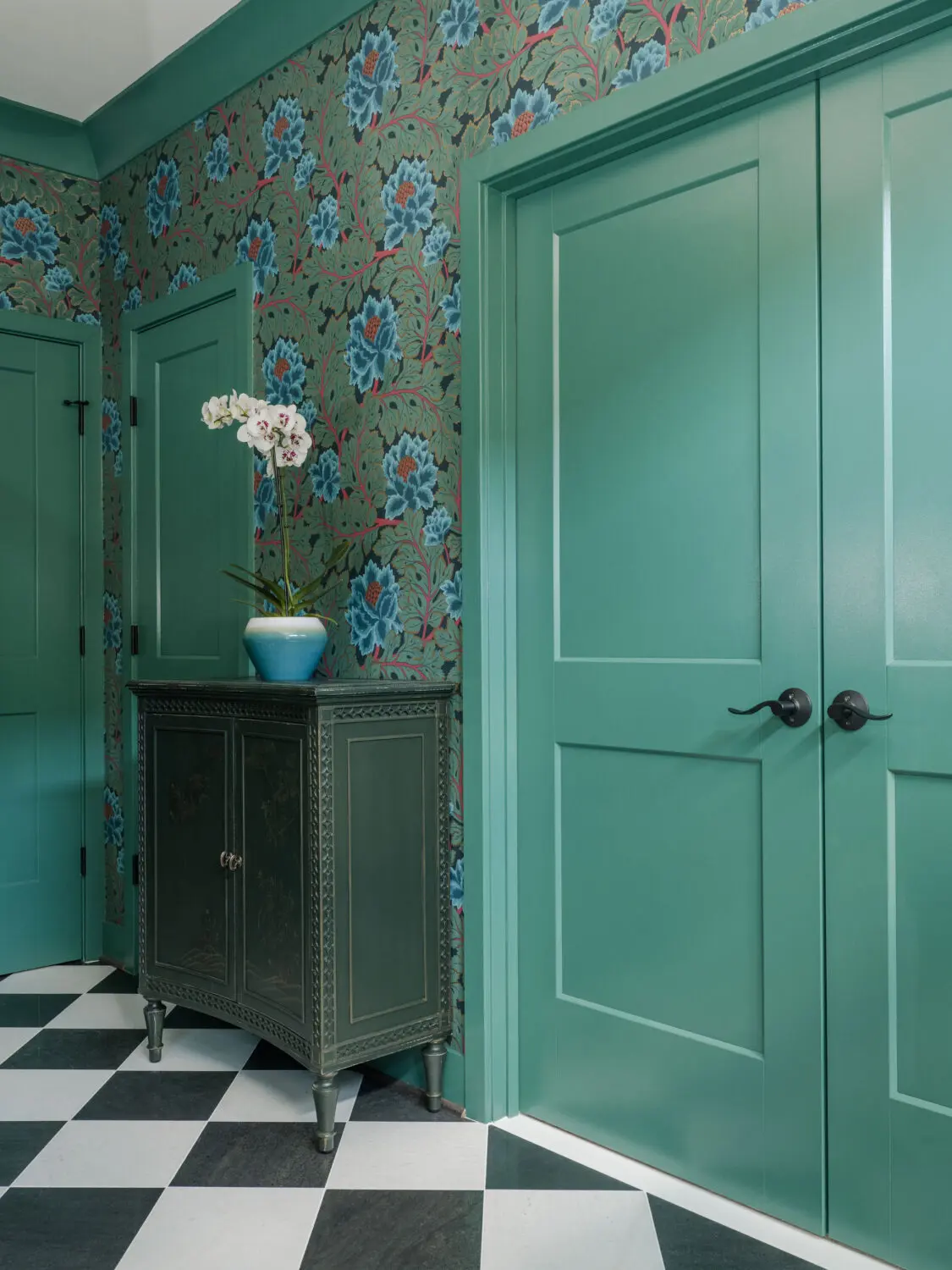 a green cabinet with a vase of flowers in front of a green door